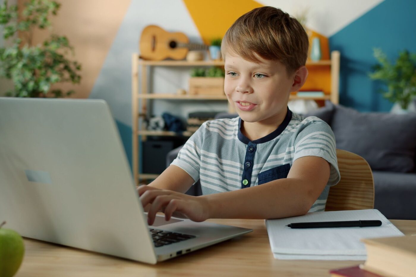 A boy smiles while working through a lesson on a laptop