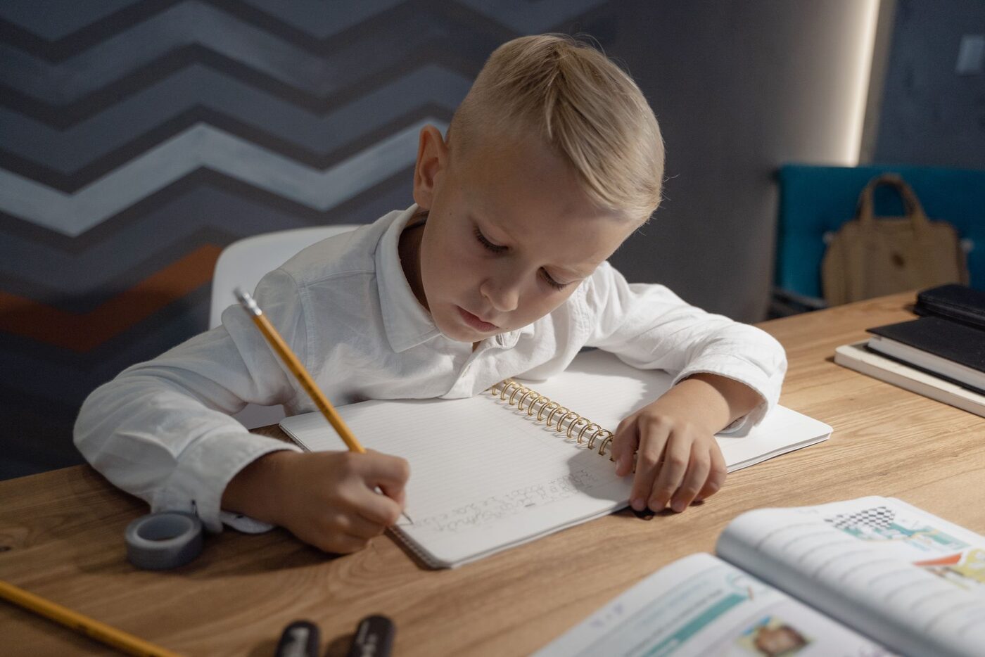 A boy writes in his exercise book at a desk at home