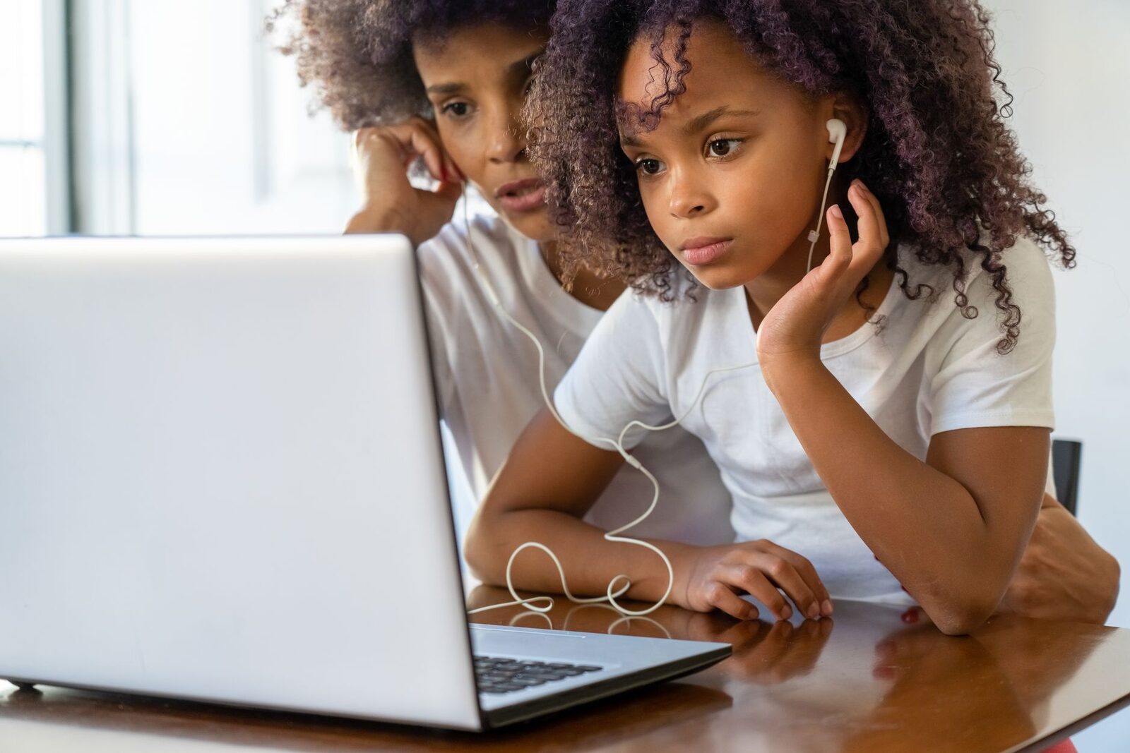 A mother and daughter look at progress reports together on a laptop