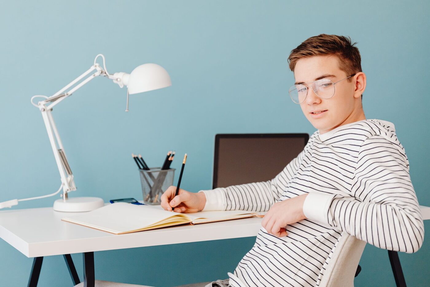 A secondary school student works at a desk with a laptop